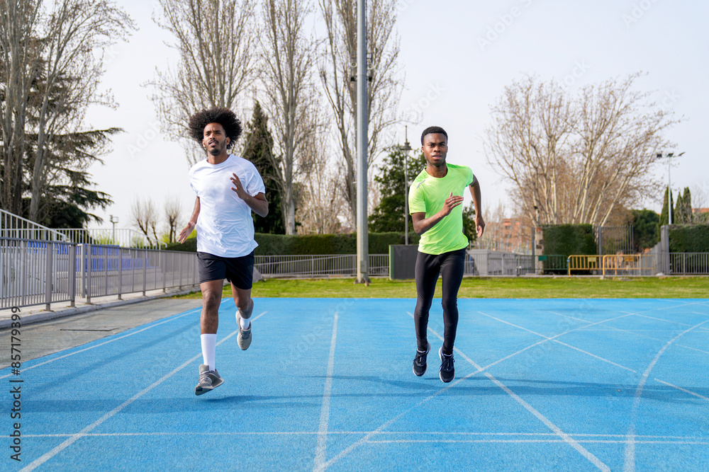 Obraz premium Two african men running on a track, one in a green shirt