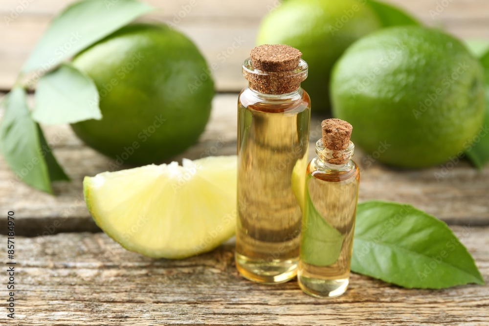 Essential oils in bottles, limes and green leaves on wooden table, closeup Essential oils in bottles, limes and green leaves on wooden table, closeup