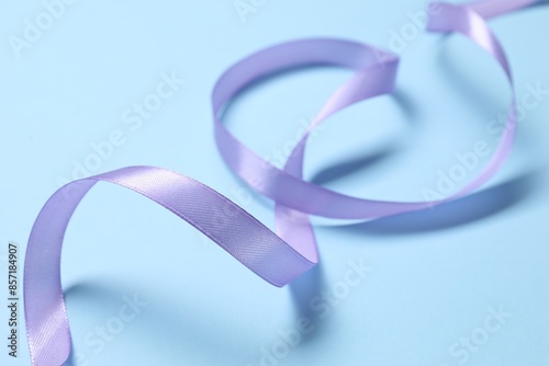 Beautiful violet ribbon on light blue background, closeup