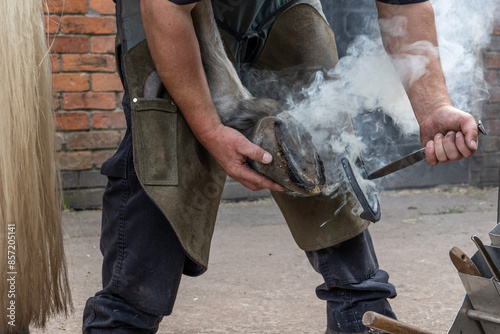 Close up of a farrier at work shoeing a horse