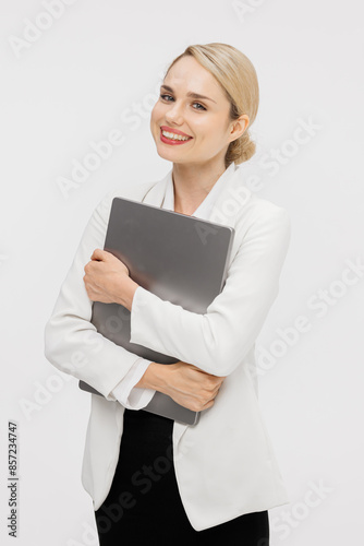 Confident blonde woman dressed in stylish business clothes against a white studio background. Business lady uses a laptop. Online work or study concept.