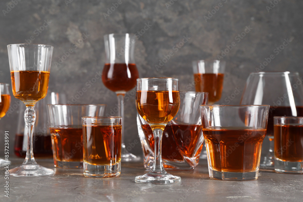 Different delicious liqueurs in glasses on grey table Different delicious liqueurs in glasses on grey table