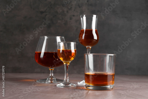 Many different liqueurs in glasses on grey textured table