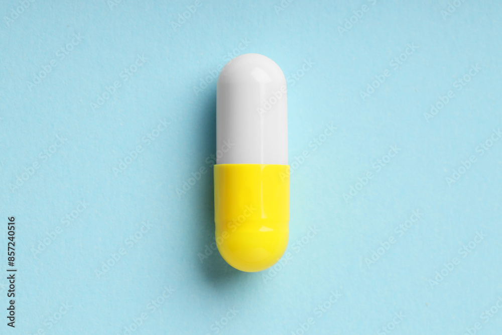One antibiotic pill on light blue background, top view One antibiotic pill on light blue background, top view