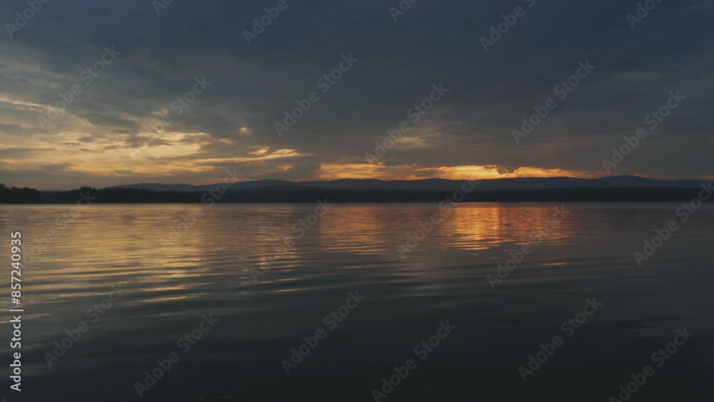 Cloudy sunset on the lake with a mirror reflection of the heavenly light on the water. Picturesque view of the lake. Beauty is in nature. Cloudy sunset on the lake with a mirror reflection of the heavenly light on the water. Picturesque view of the lake. Beauty is in nature.