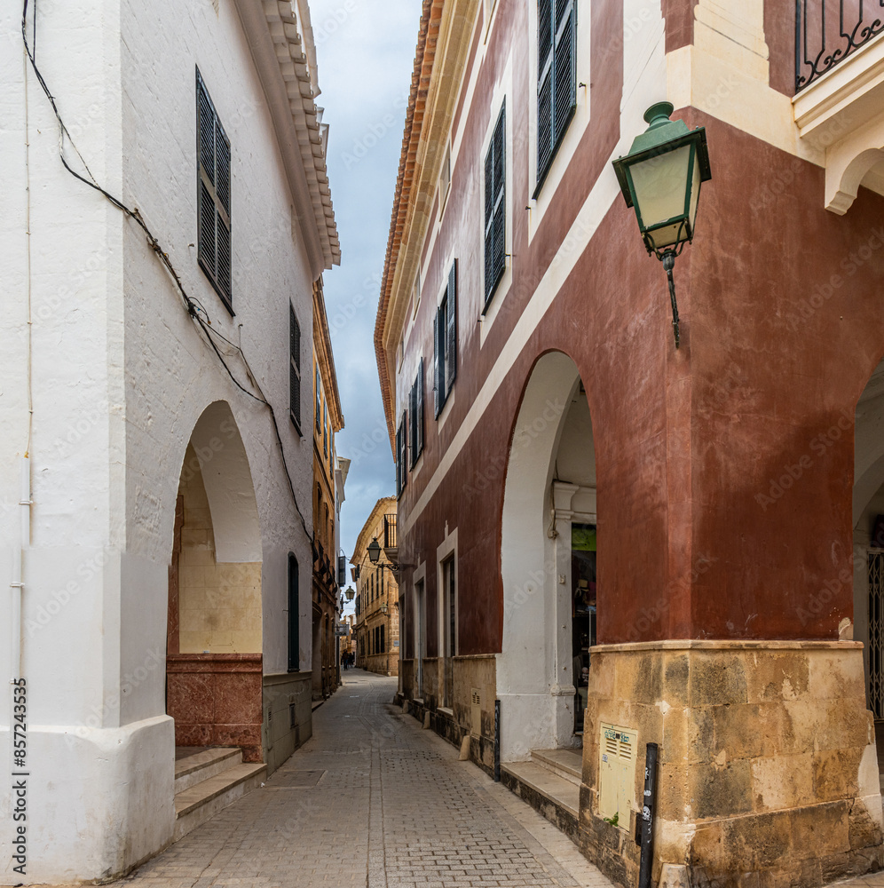 Fototapeta premium Charming and picturesque streets of Ciudadela. Cozy arcades formed by arches in various shades of color. Menorca, Spain