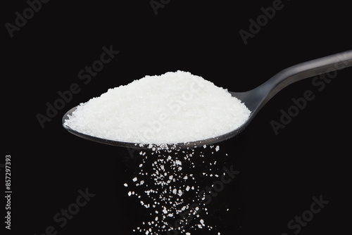 Falling natural white grains sugar on a black background. Shallow depth of field