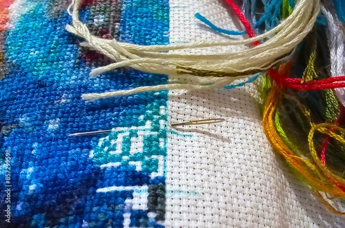 closeup of needle put into cross-stitch embroidery. photo