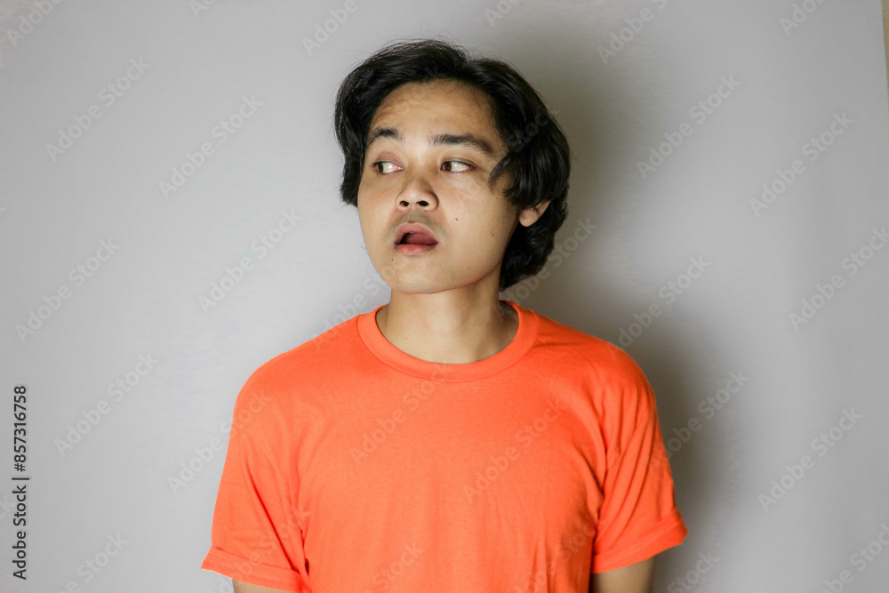 Portrait of an Asian Indonesian young man wearing a orange shirt with a random expression when photographed with an isolated white background Portrait of an Asian Indonesian young man wearing a orange shirt with a random expression when photographed with an isolated white background