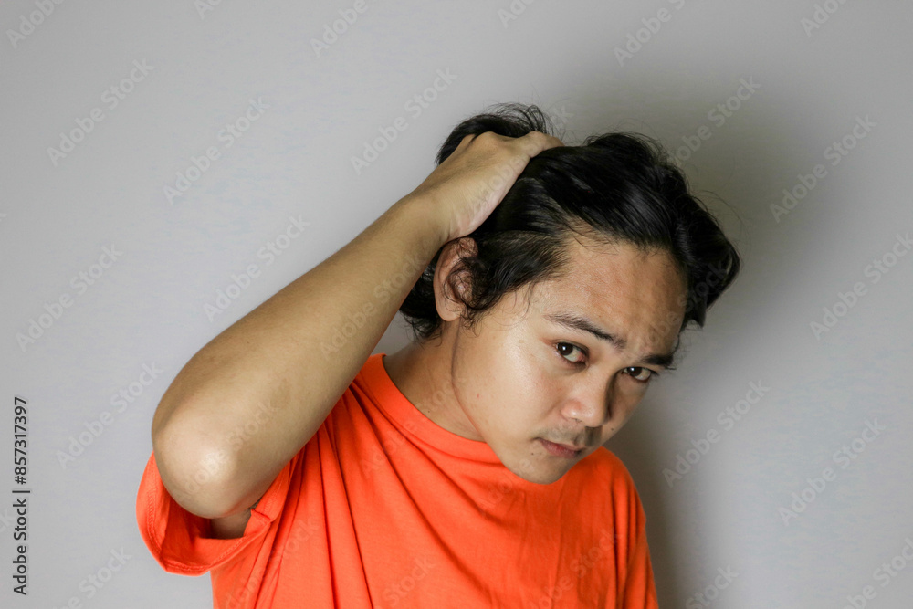 Portrait of an Asian Indonesian young man wearing a orange shirt with a random expression when photographed with an isolated white background Portrait of an Asian Indonesian young man wearing a orange shirt with a random expression when photographed with an isolated white background
