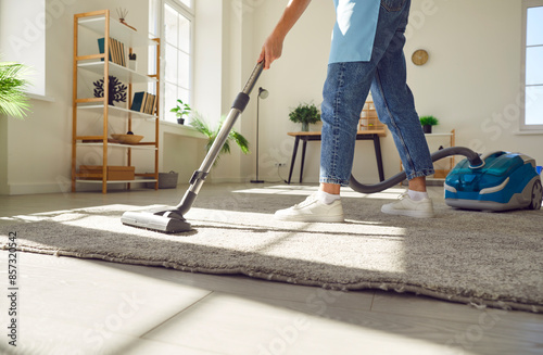 Obraz na plátně Cropped photo of woman cleaning with vacuum cleaner carpet in the living room at home