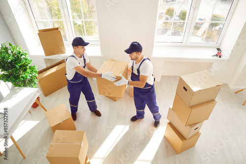 During relocation or delivery, two movers are seen carrying boxes into either a home or office space. Coordinated efforts reflect the professionalism of a relocation service.