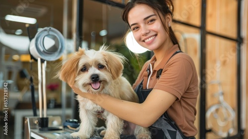 A happy woman groomer stands with a cute, freshly-groomed dog in a modern grooming salon. The environment is clean and welcoming, highlighting professional pet services. photo