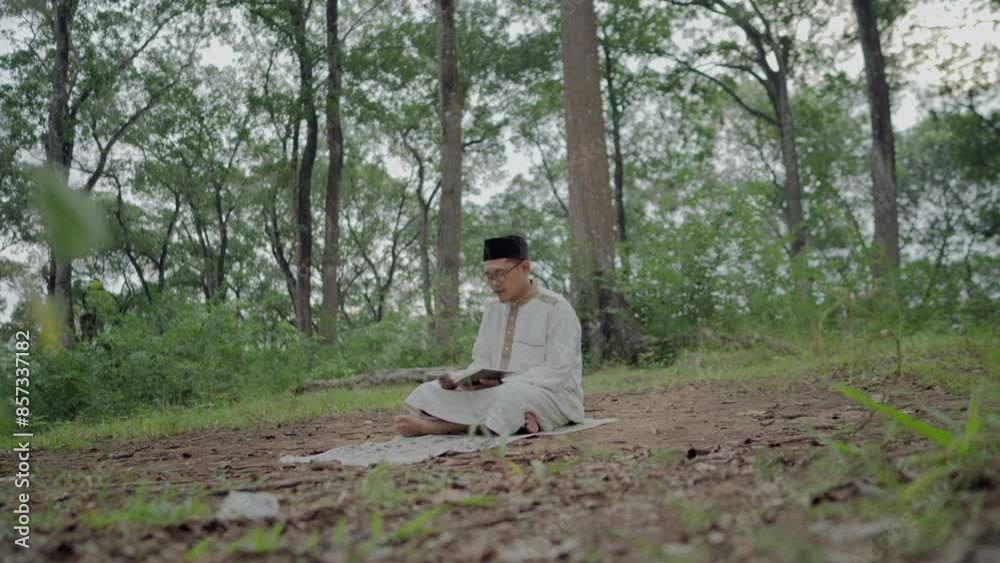 a young Asian Muslim is reading the Koran in the forest during the month of Ramadan a young Asian Muslim is reading the Koran in the forest during the month of Ramadan