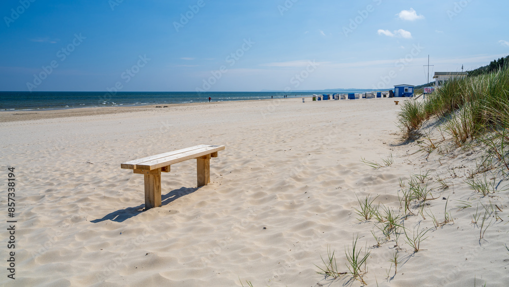 A lonely bench stands on beach, on white sand, coastal dunes with beach grass. Usedom, Germany A lonely bench stands on beach, on white sand, coastal dunes with beach grass. Usedom, Germany