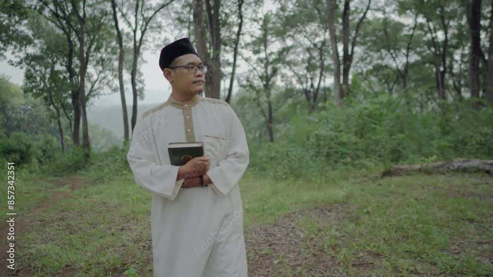 a young asian muslim is holding a quran and walking in the forest a young asian muslim is holding a quran and walking in the forest