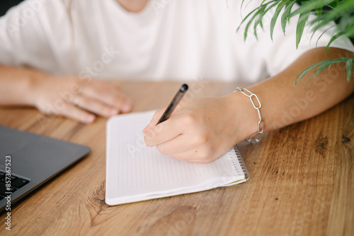 Woman writes by her left hand in a notebook  photo