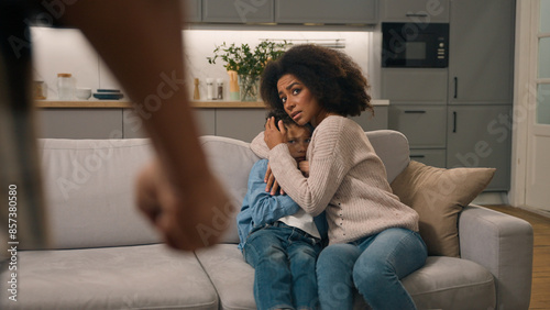 Domestic violence African American ethnic family. Aggressive man father threaten beat clenched fist back view scared mother protect frightened little boy child kid suffering physical abuse indoor home