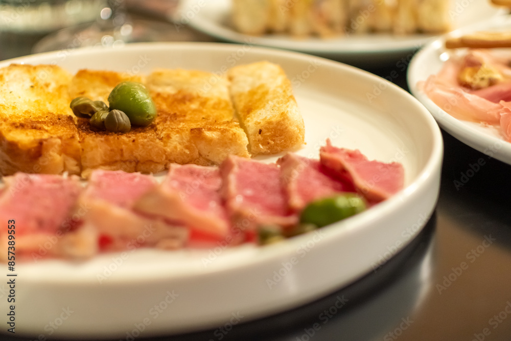 Green olives and capers on pieces of fried bread close-up on blurred background of delicious snacks Green olives and capers on pieces of fried bread close-up on blurred background of delicious snacks