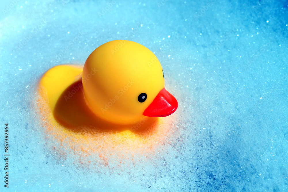 A rubber duck floats in the foam in the bathtub. A rubber duck floats in the foam in the bathtub.