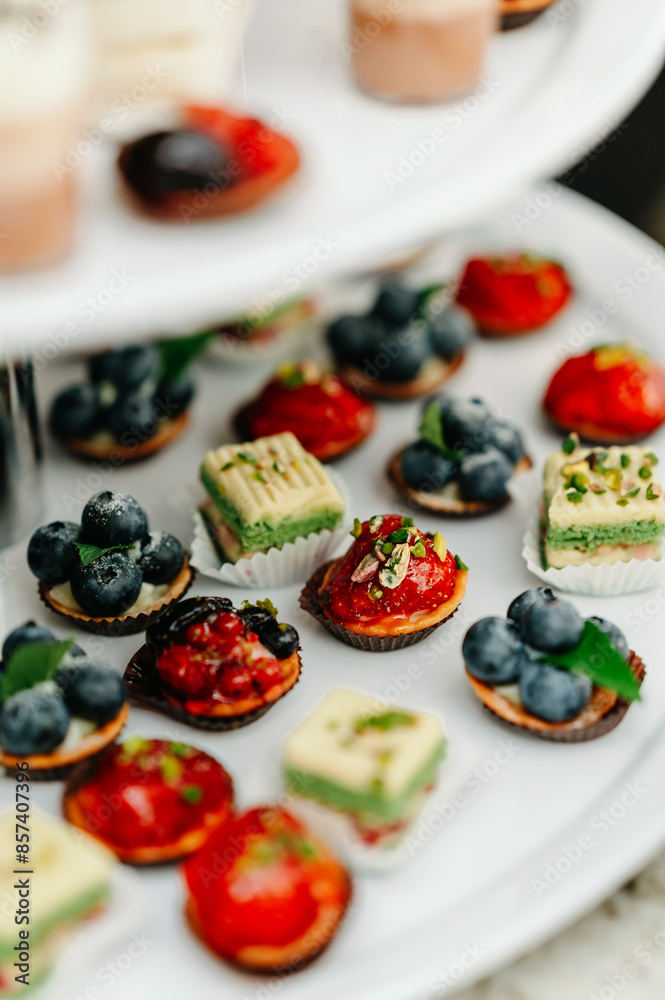 Close-up of assorted desserts featuring berries and pistachios on a tiered tray, perfect for events.