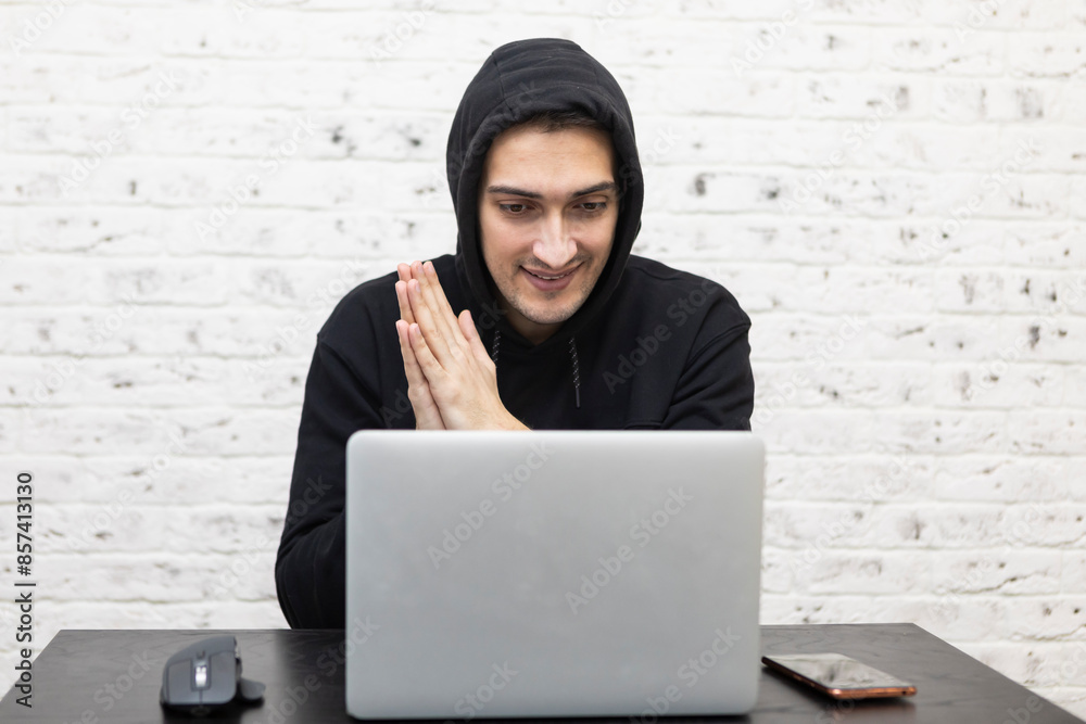 Happy guy in hood sitting at laptop and celebrating Happy guy in hood sitting at laptop and celebrating