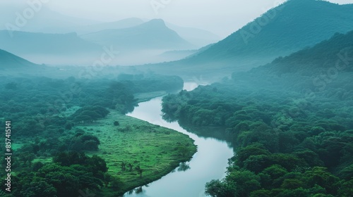  Aerial view of a river snaking through a valley encircled by mountains on a foggy day © Jevjenijs