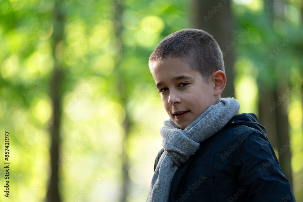 Portrait of young boy stands in a wooded area, gazing to the side with a thoughtful expression. Portrait of young boy stands in a wooded area, gazing to the side with a thoughtful expression.