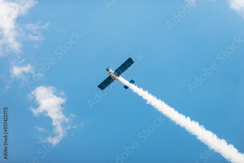 Quadro em tela A small plane rises in a blue sky. Light aircraft with a contrail
