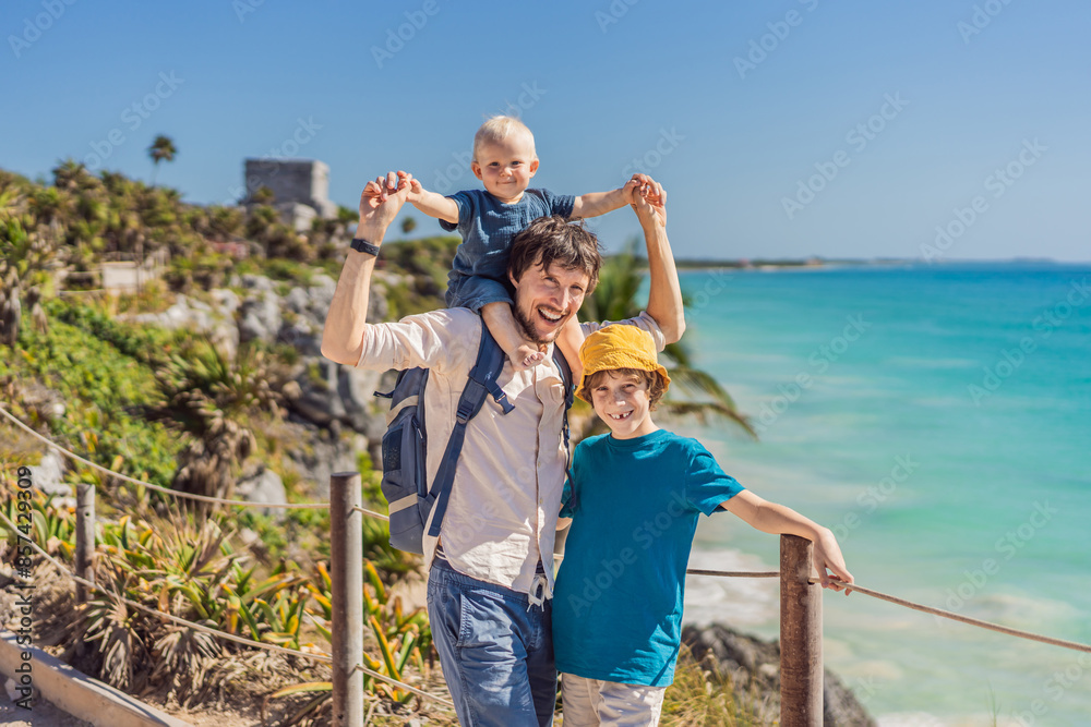 Father and two sons tourists enjoying the view Pre-Columbian Mayan walled city of Tulum, Quintana Roo, Mexico, North America, Tulum, Mexico. El Castillo - castle the Mayan city of Tulum main temple