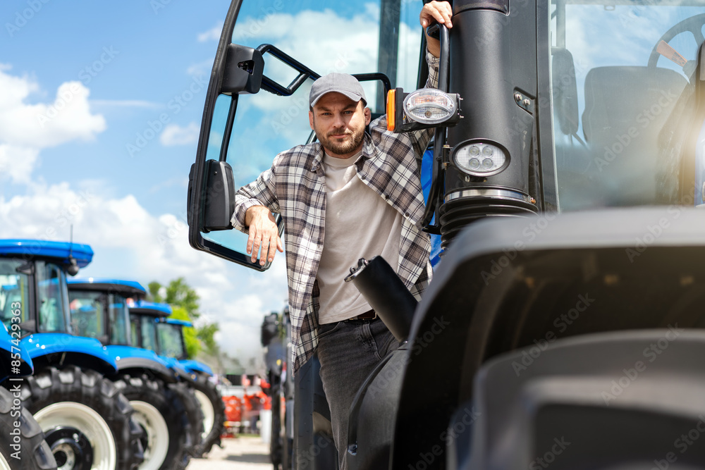 Naklejka premium Portrait of man farm tractor driver posing on tractor.