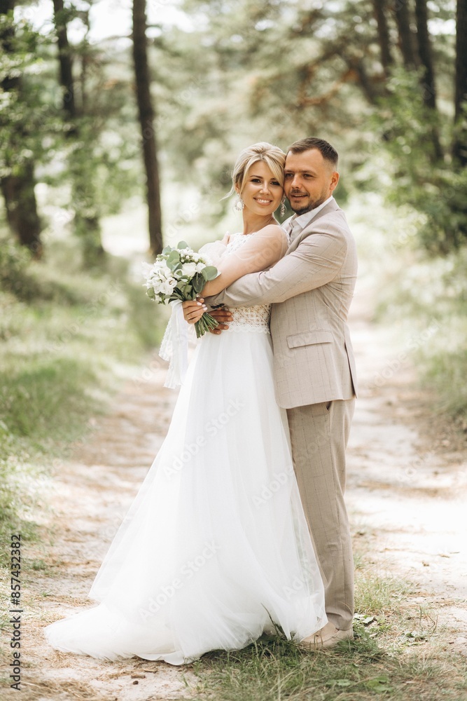 Wedding couple bride and groom hugging in pine forest, sunlight filtering through the trees, highlighting their joyful expressions. Wedding couple bride and groom hugging in pine forest, sunlight filtering through the trees, highlighting their joyful expressions.