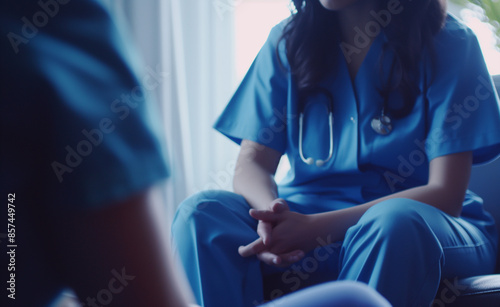A nurse in scrubs with hands clasped, showing a stethoscope around the neck. © Curioso.Photography