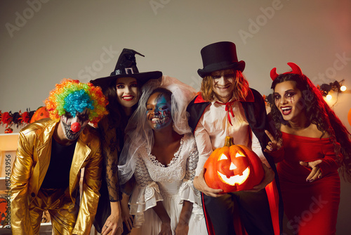 Fotografi Happy young people dressed up as different spooky characters, with scary makeup on faces having fun at Halloween costume party