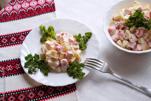 Obraz na płótnie Homemade crab stick salad typical of modern Ukrainian cuisine and other Eastern European cuisines Traditional Ukrainian food on the table with embroidered tablecloth. w salonie