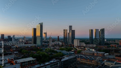 The golden hour casts a warm glow over Manchester, highlighting The Great Jackson Street skyscraper district near Deansgate