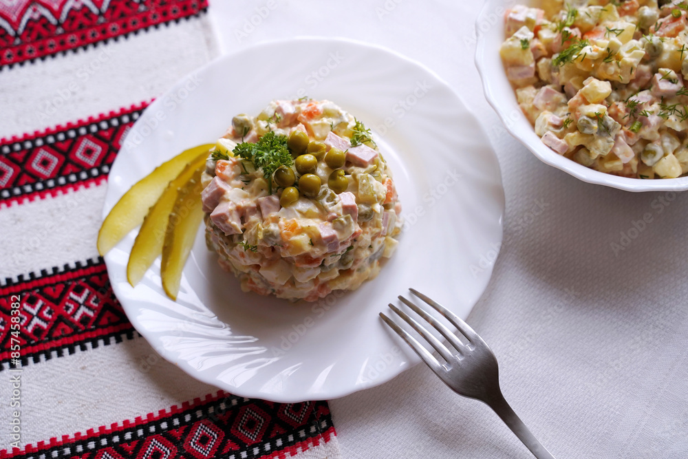 Olivier salad, traditional salad dish of post Soviet cuisine. Traditional Ukrainian food on the table with embroidered tablecloth.