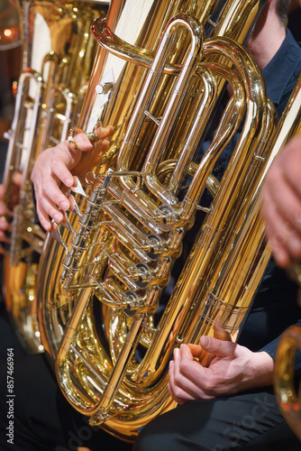 Hände, die eine glänzende Messingtuba spielen, Nahaufnahme der Finger des Musikers und der Ventile des Instruments. photo