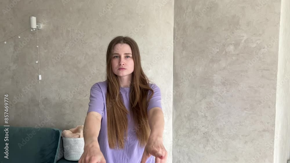 Woman practices expressive dance in a modern living room with cozy, minimalist decor, showcasing various gestures and body movements
