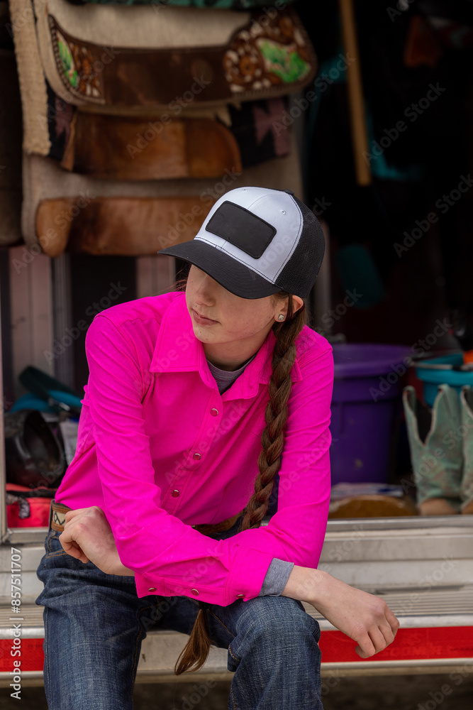 Barrel racer Cowgirl in bright pink shirt and hat in horse trailer Barrel racer Cowgirl in bright pink shirt and hat in horse trailer