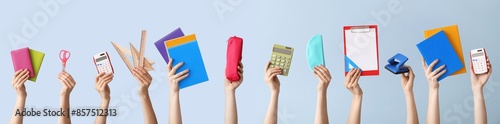 Many hands with school supplies on light blue background