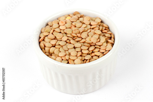 Pile of brown raw dry lentils in ceramic bowl isolated on white background