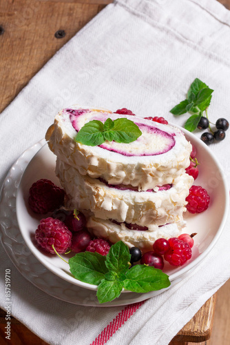 Obraz na płótnie Meringue roll with whipped cream and currant curd, served with berries on a ceramic plate. Rustic style. w salonie