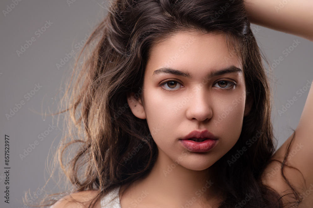 Beautiful latin woman touching her hair on gray background Beautiful latin woman touching her hair on gray background