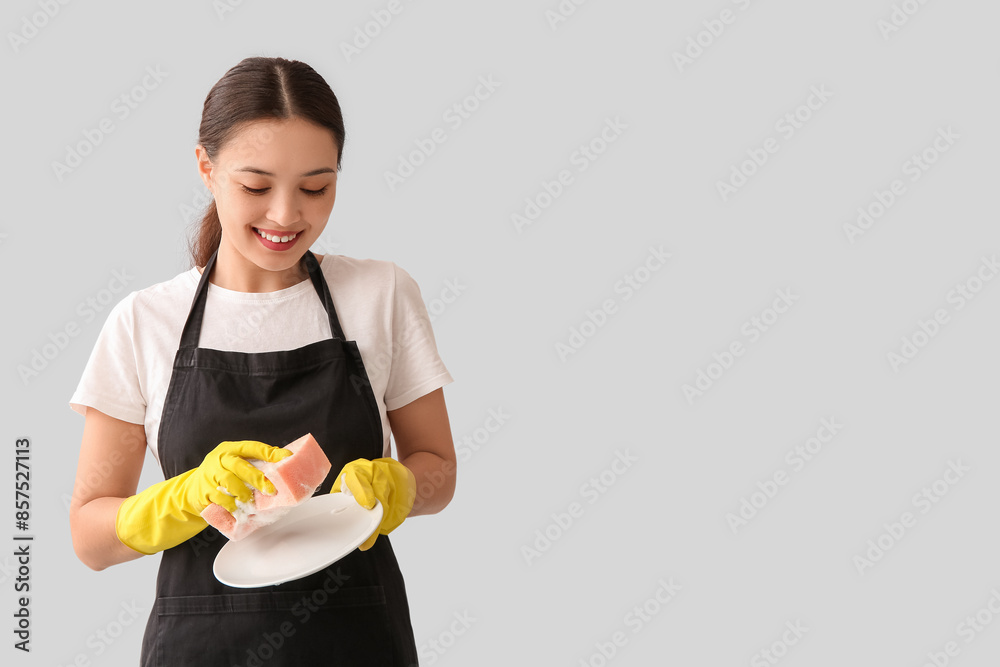 Young woman washing plate on light background Young woman washing plate on light background