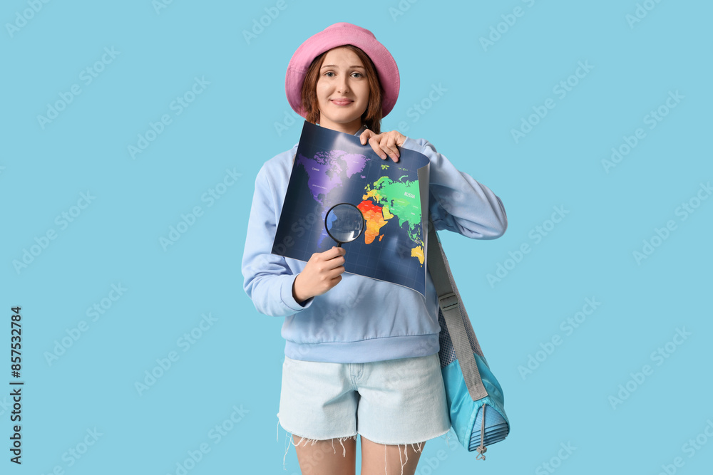 Young woman showing map with  magnifying glass on blue background. Travel concept