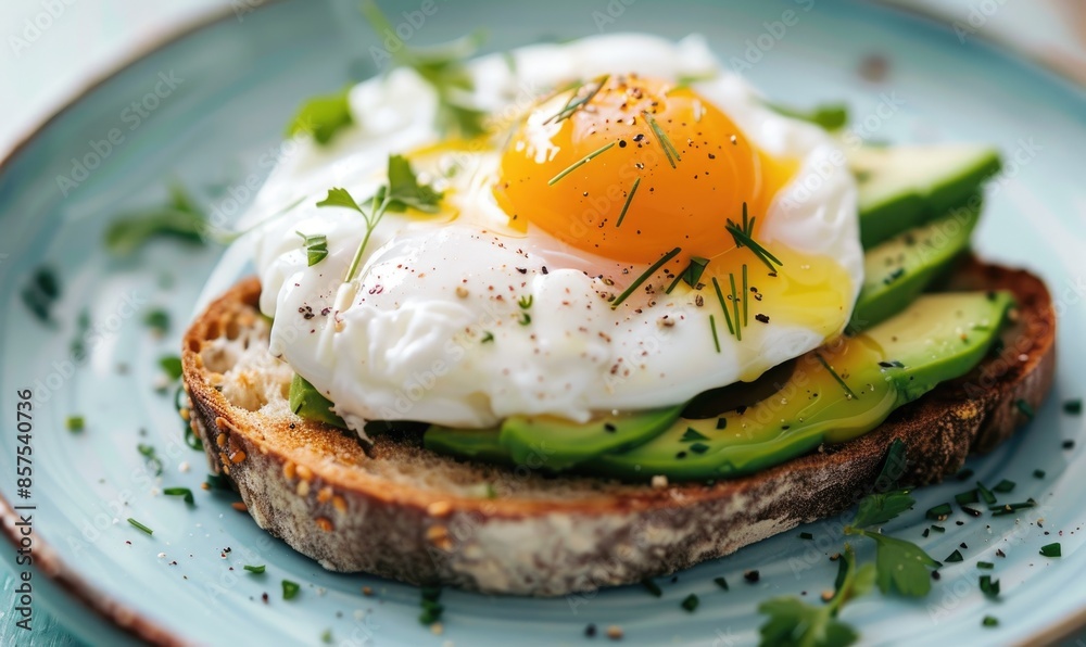Avocado toast with poached egg and herbs on a pastel blue plate Avocado toast with poached egg and herbs on a pastel blue plate