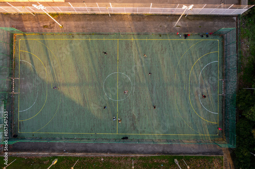 Aerial drone top view of mini football soccer field with artificial plastic cover with playing people. Public sport ground in city at sunny summer day drone view photo