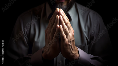 Close-up of a man's hands clasped together in prayer against a dark background, conveying a sense of devotion and contemplation. Concept of faith, spirituality, and introspection. 