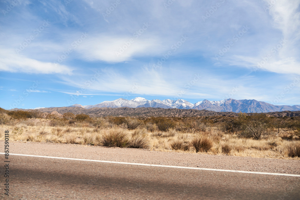 On the side of a road in Mendoza, Argentina, a landscape stretches out with the mountains of the Andes in the distance on the horizon. On the side of a road in Mendoza, Argentina, a landscape stretches out with the mountains of the Andes in the distance on the horizon.